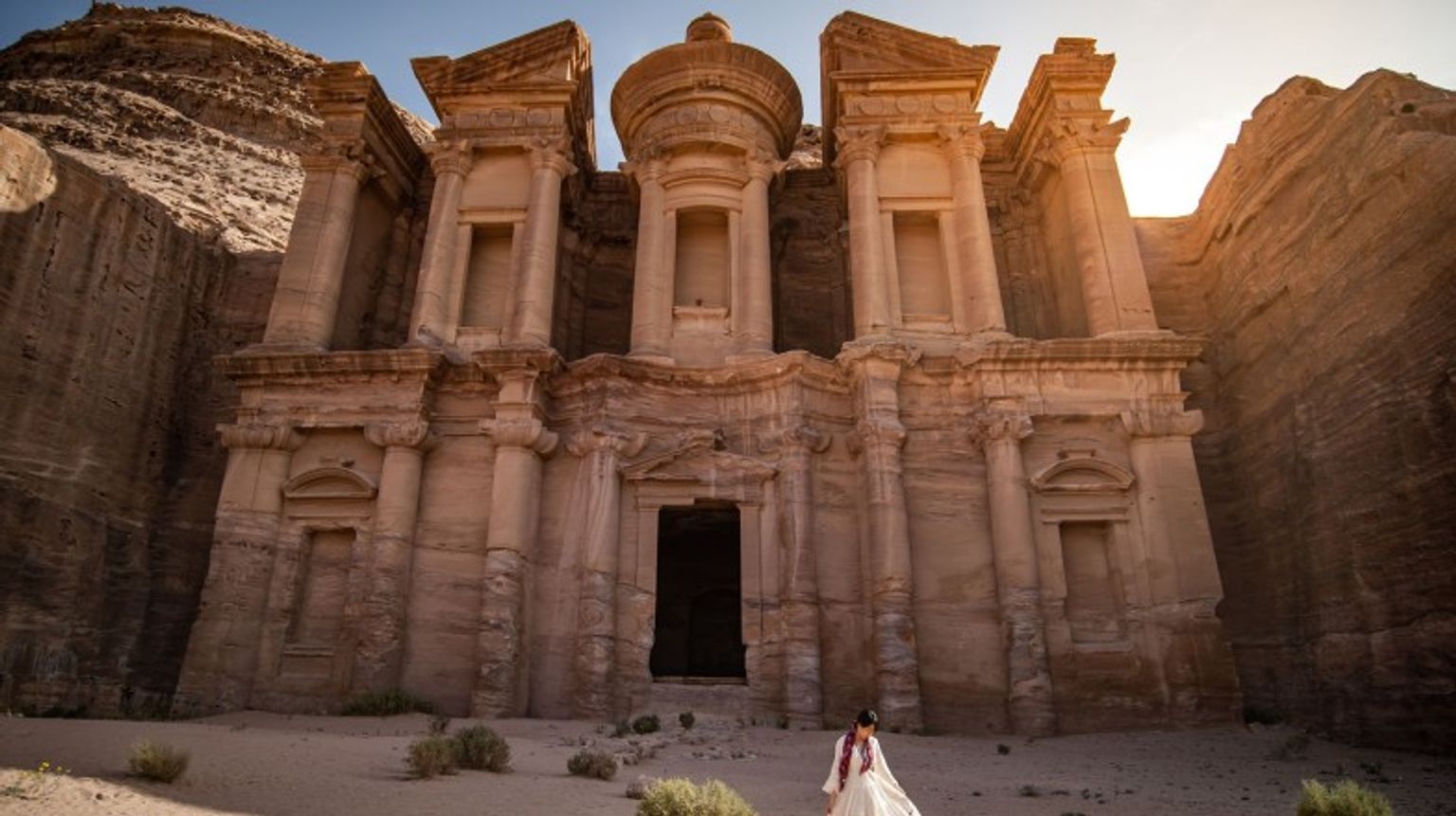 A woman in white dress standing at Ad Deir in Petra during her one week in Jordan.