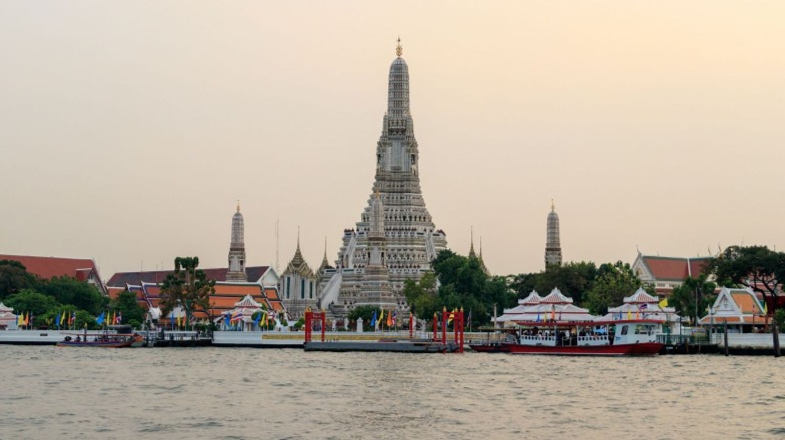 The front view of Wat Arun Temple with Chao Phraya River on a cloudy day in Thailand in May.