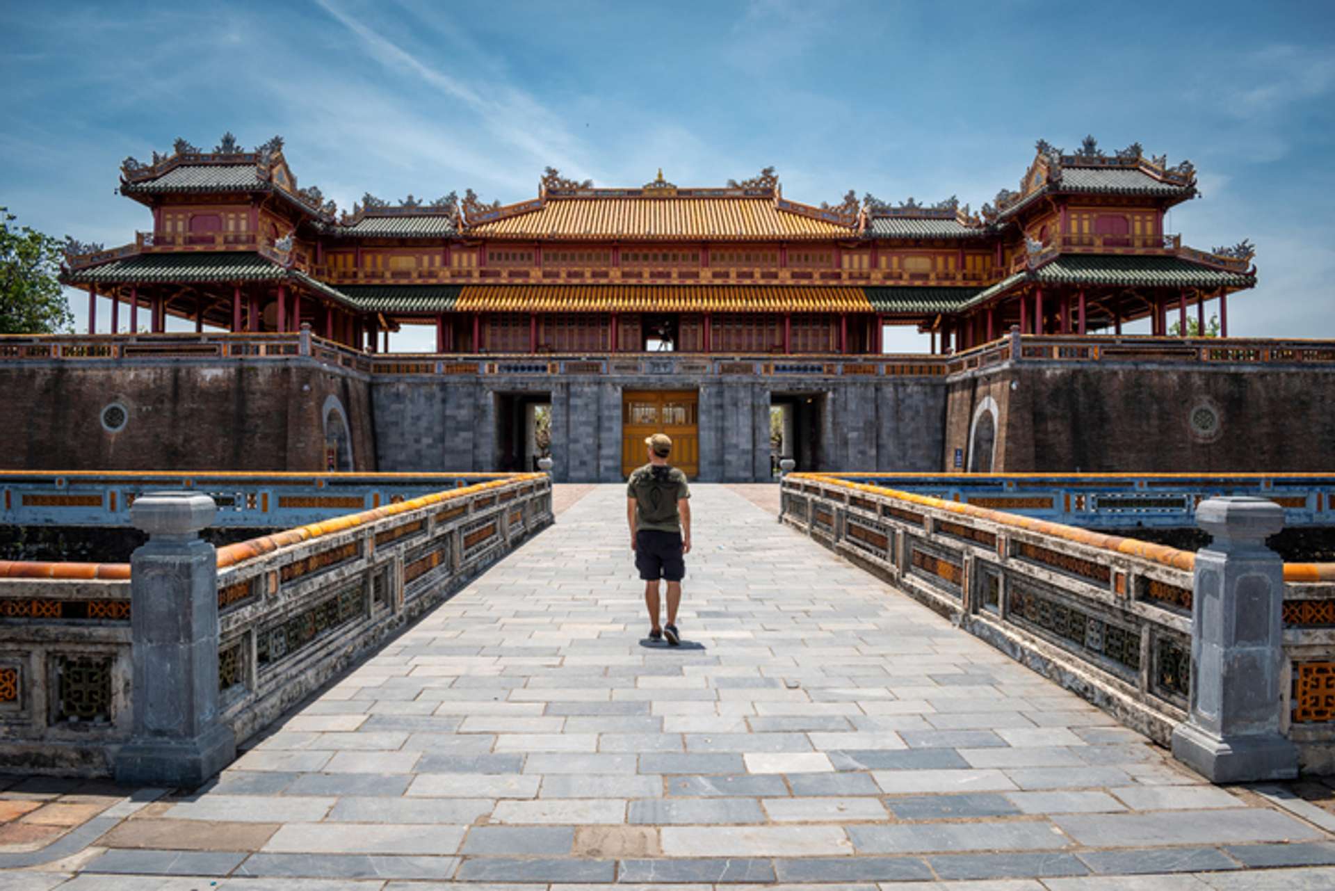 A man stands at the ancient stone gate of an ancient building in Hue, Vietnam