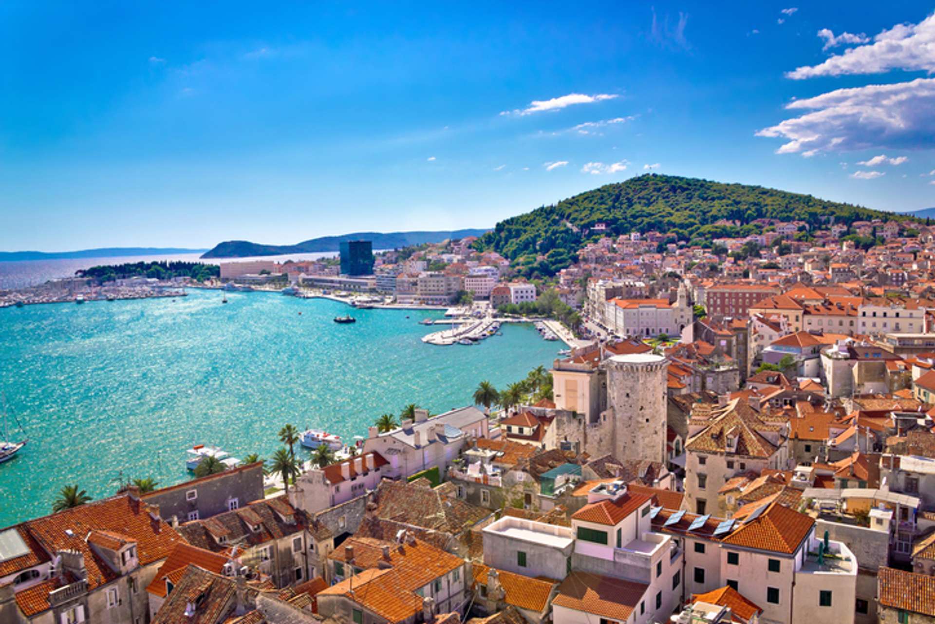 A town next to a blue sea with orange roofed homes