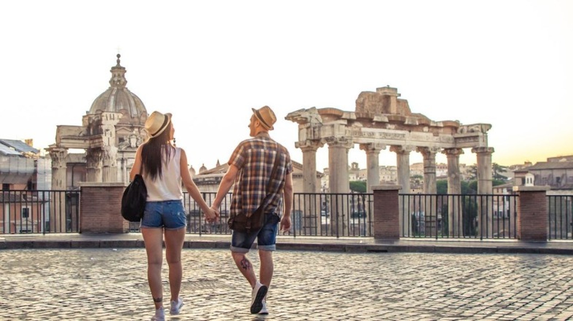Step back in time and visit the Roman Forum, one of the must-see historical sites and top places to visit in Italy, brimming with ancient ruins and stories. A happy couple walking hand in hand towards Roman Forum, one of the best places to visit in Italy.