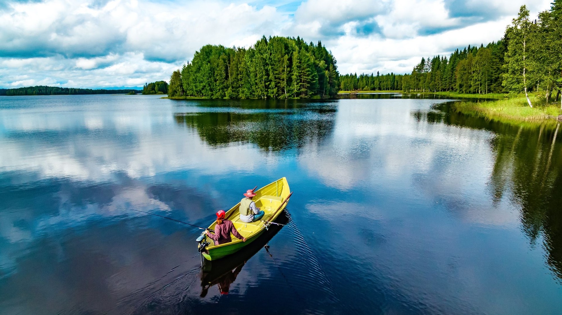 Experience the thrill of fishing during your 10 days in Finland, where tranquil lakes and breathtaking scenery provide the ultimate backdrop for a peaceful retreat. A couple fishing in the blue summer lake on a clear day on their 10 days in Finland trip.