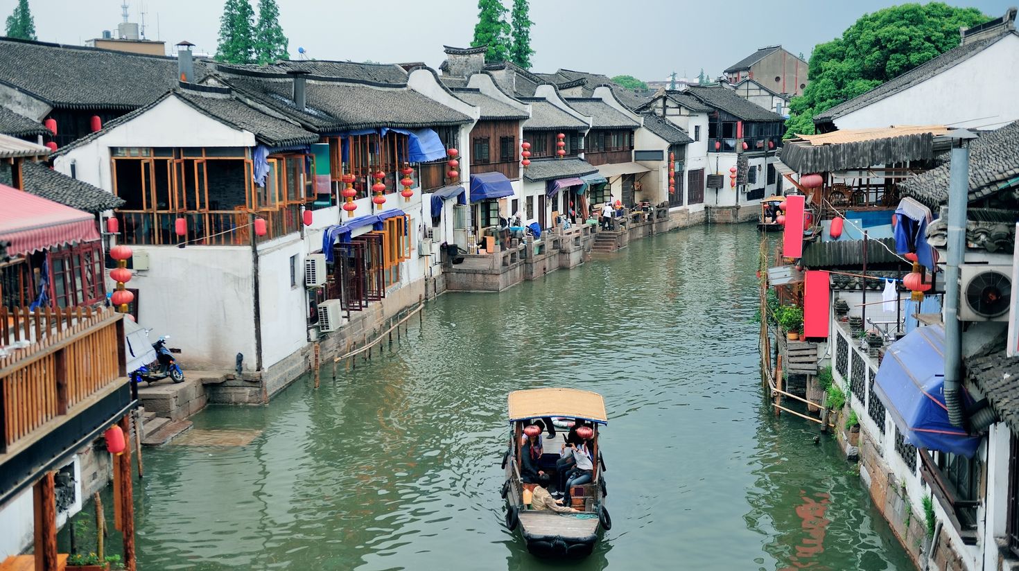 Tourists taking photos of the Zhujiajiao Water Town from a small boat