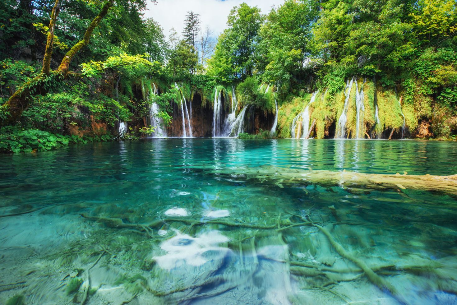 The still waters with waterfalls in the distance at Plitvice National Park. 
