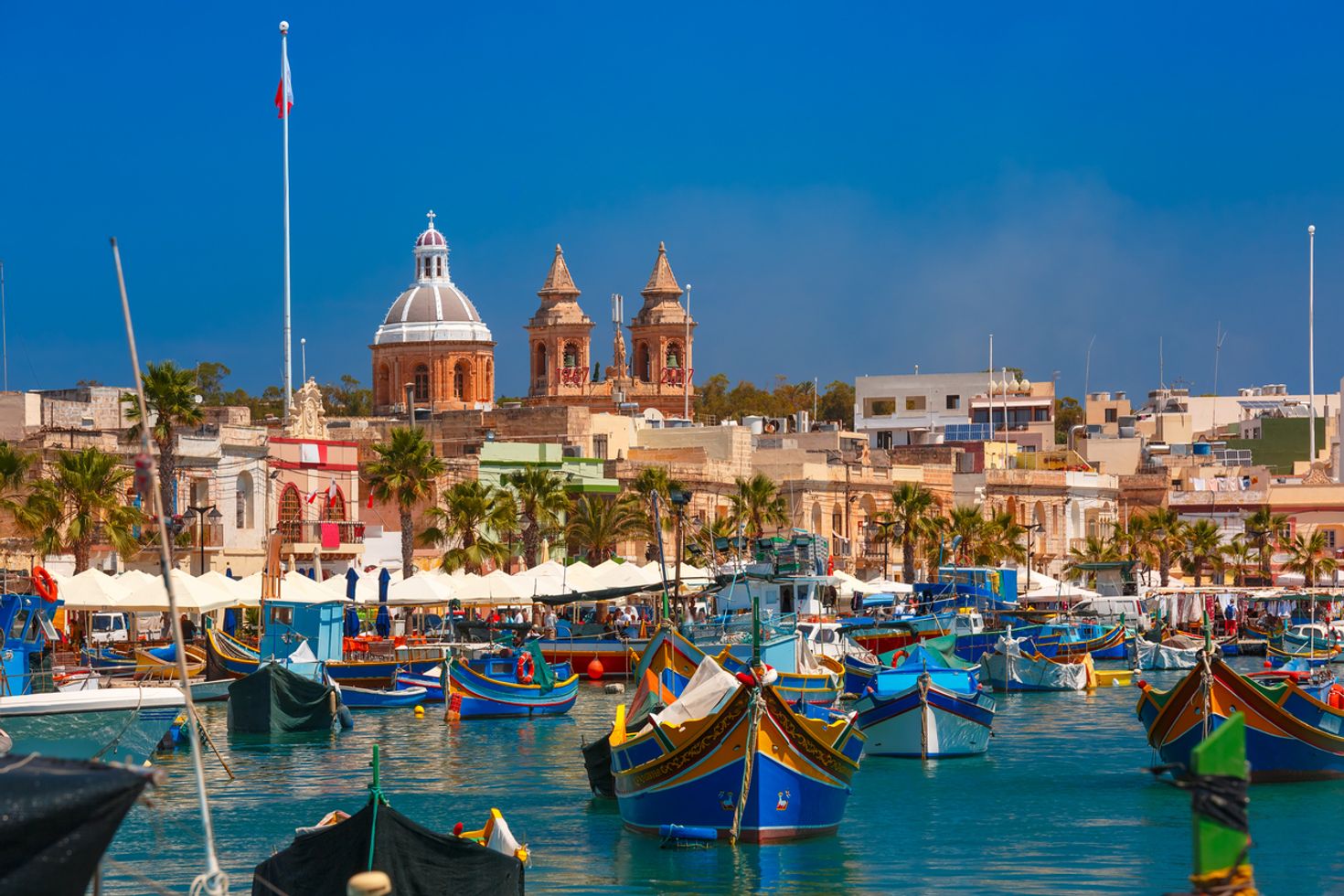 Boats on the water with traditional building in the background at Marsaxlokk. 