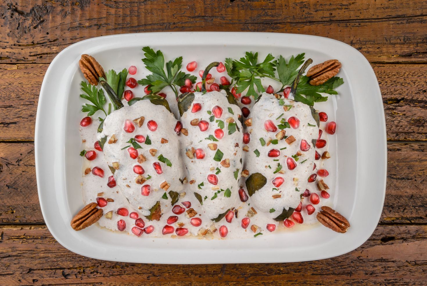 The traditional Mexican dish Chiles en Nogada on a white place set on a table. 