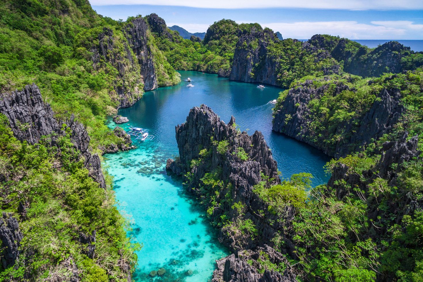 An arial view of blue water of a lagoon surrounded by dense forest in El Nido in Palawan