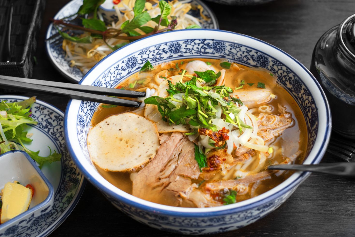 Traditional Pho in a bowl set on the table with other food items. 