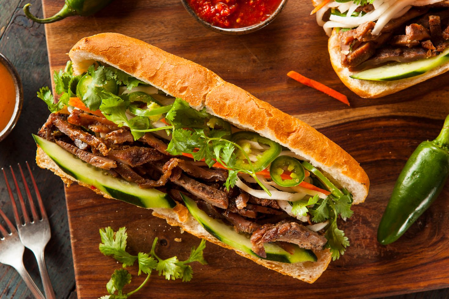 Banh Mi - a famous Vietnamese sandwich set on a table next to chilies and bread. 