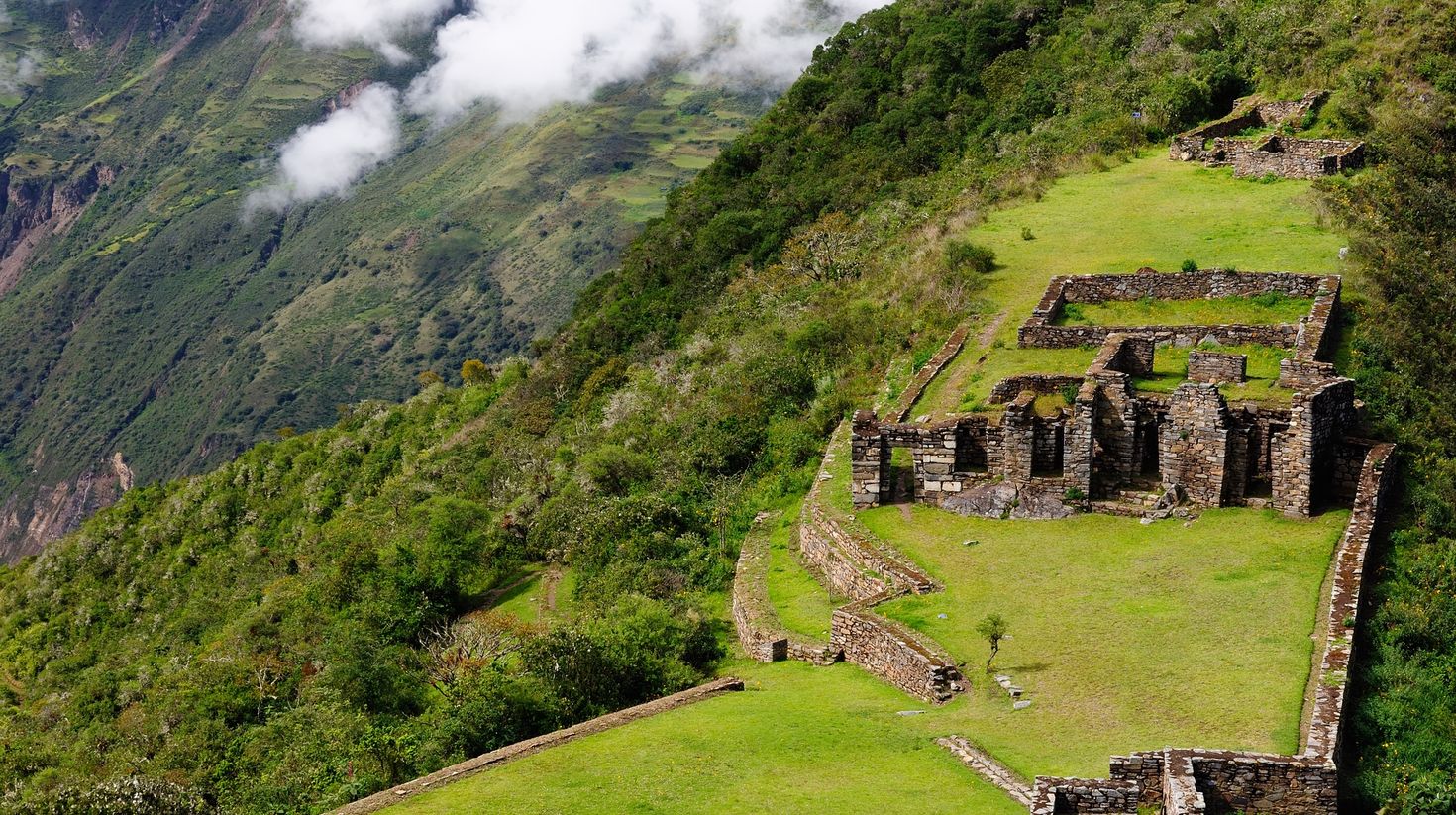 Dense forest surrounding Choquequirao in Cusco with clouds on the hills in the background. 