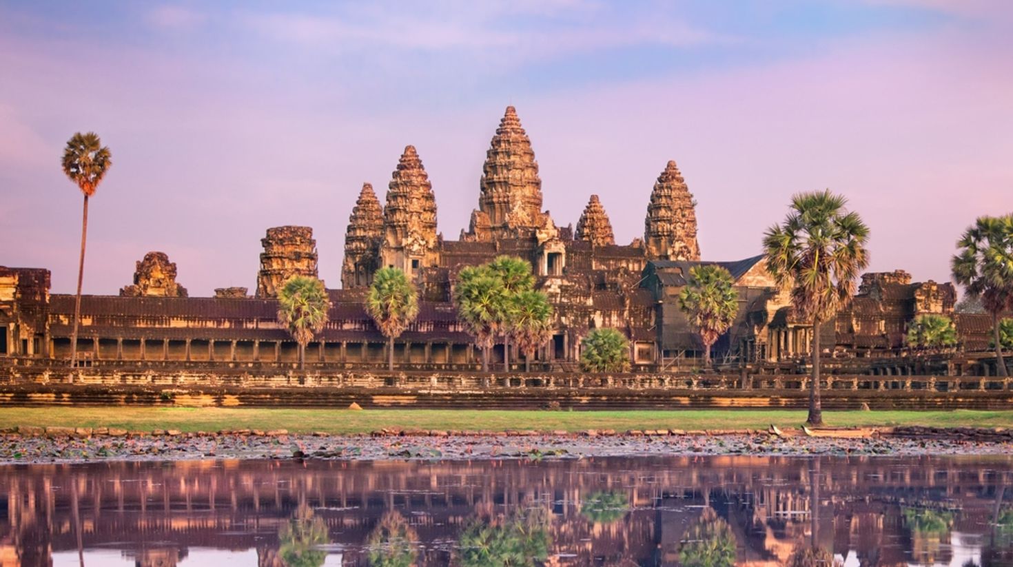 The ancient ruins of Angkor Wat with its reflection in the water during sunset. 