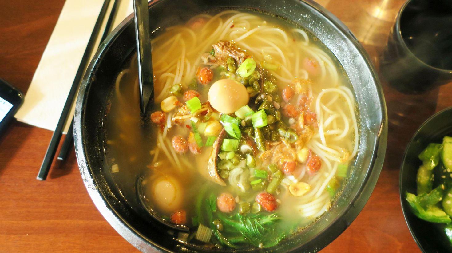 A bowl of soupy noodles with meat and vegetables