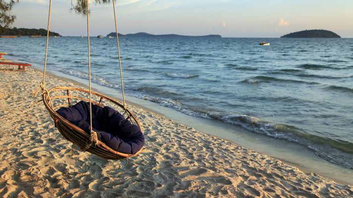 A swing hung on the beach overlooking the ocean. 
