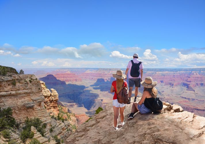 Three tourists taking a break and enjoying the view of the Grand Canyon. 
