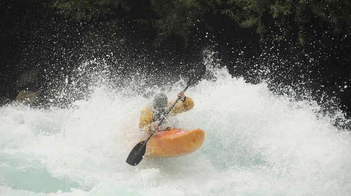 A kayaker on a yellow kayak paddling through extreme rapids in Rio Futaleyfu. 