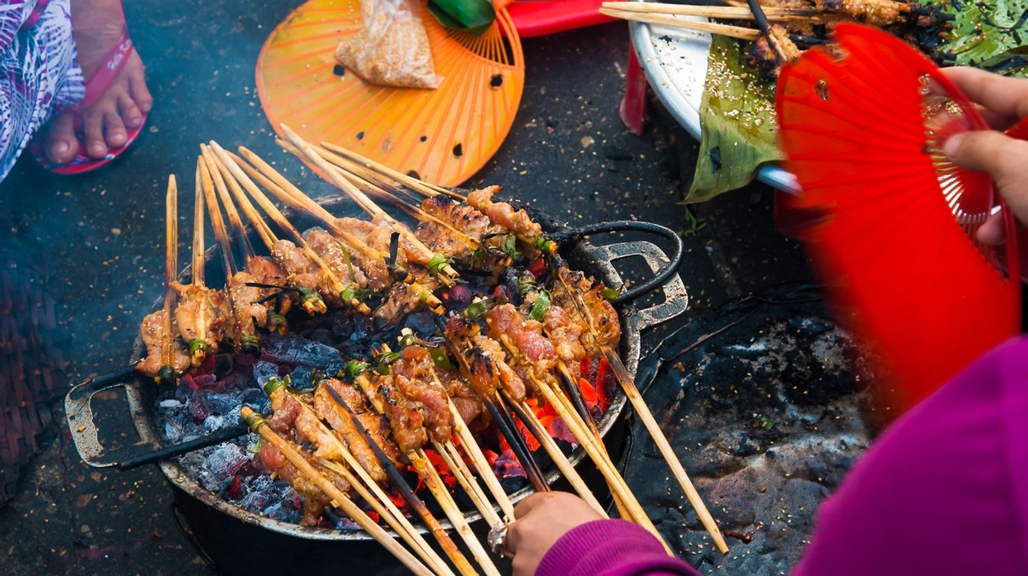 A hawker prepares skewered grilled meat in Hoi An, Vietnam.