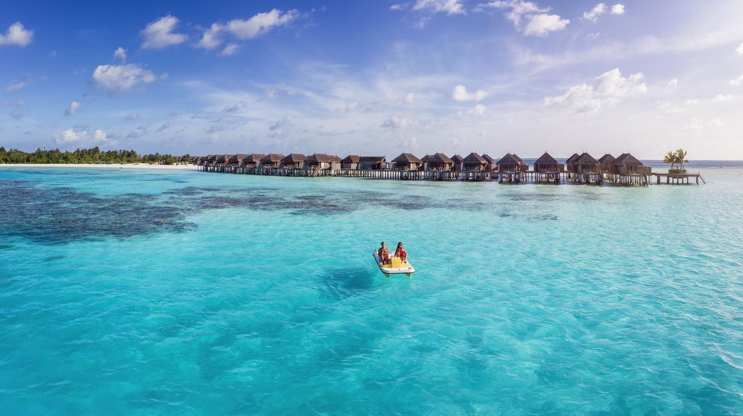 A couple enjoying a pedalo boat ride in clear waters in the Maldives.