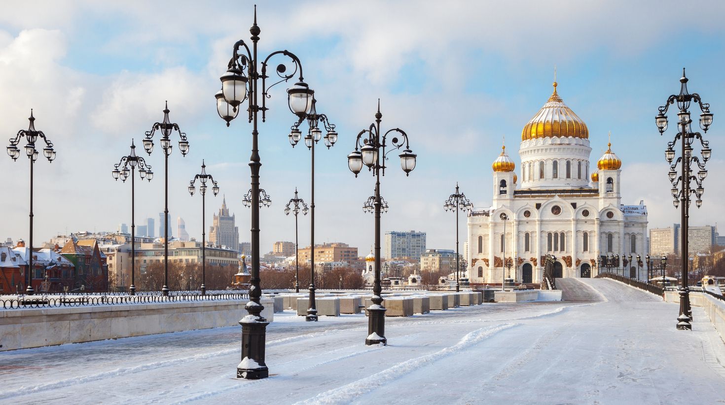 View of a white building  and street lamps with the road covered in snow