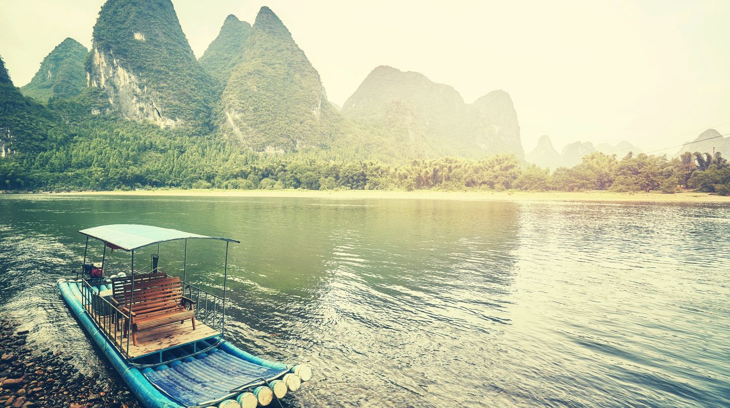 Raft made of bamboo floating on a river surrounded by hills