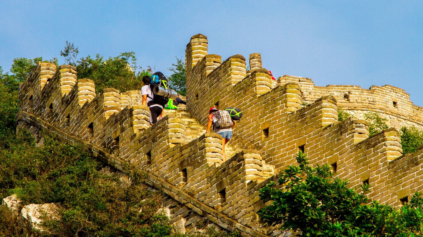 Tourists carrying backpacks hiking up the Great Wall of China