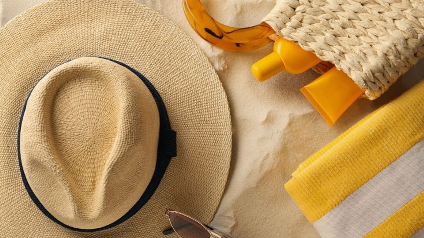 Sunscreen, straw hat and sunglasses on the table.