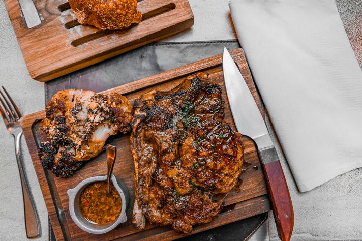 steak dish on a wooden plate with knife and fork on either side