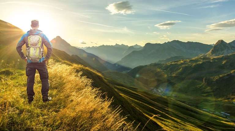 A hiker in the Alps of Austria in October during dusk admiring the beauty.
