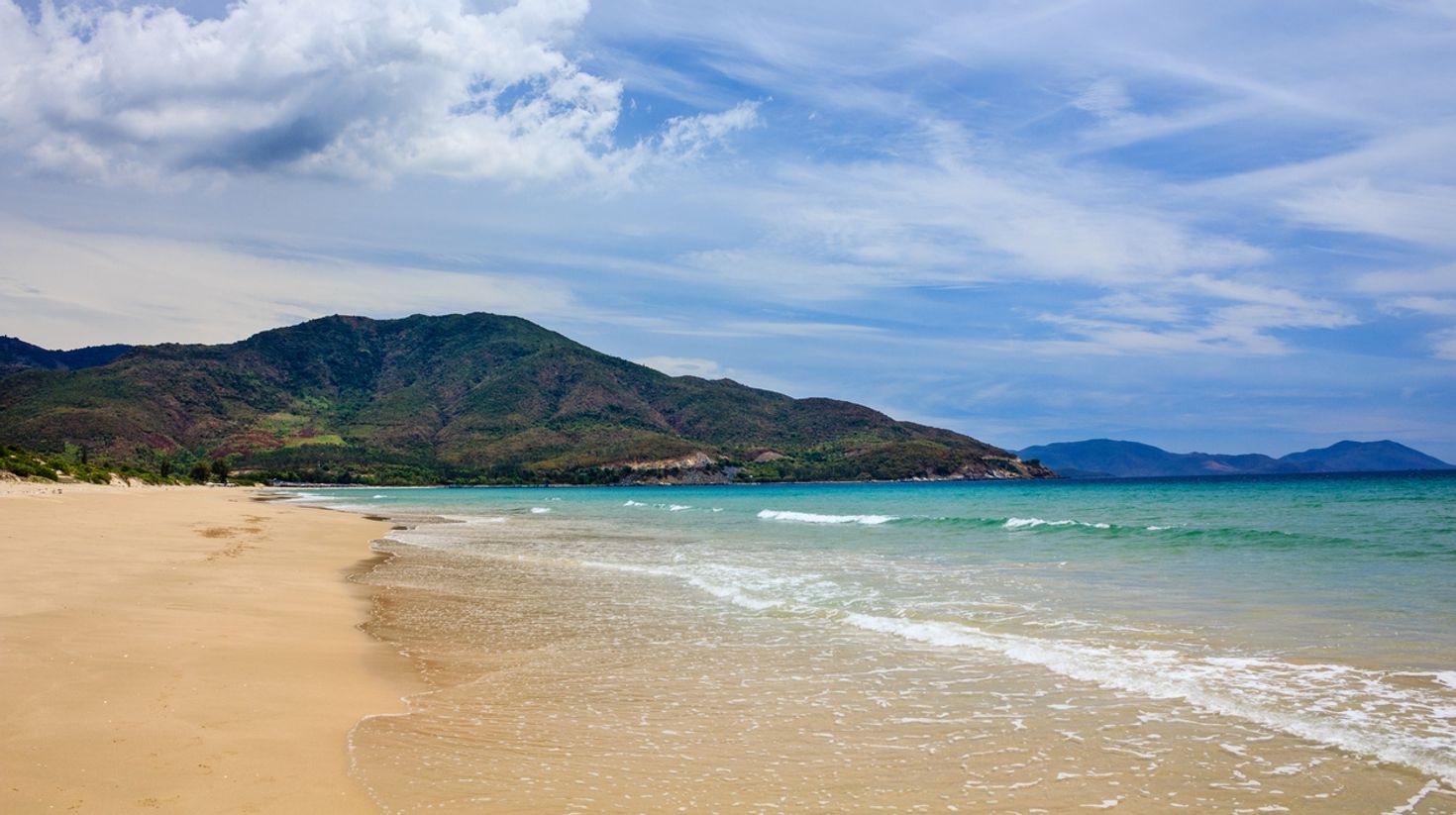 A view of Bai Dai beach with hills in the background on a sunny day.