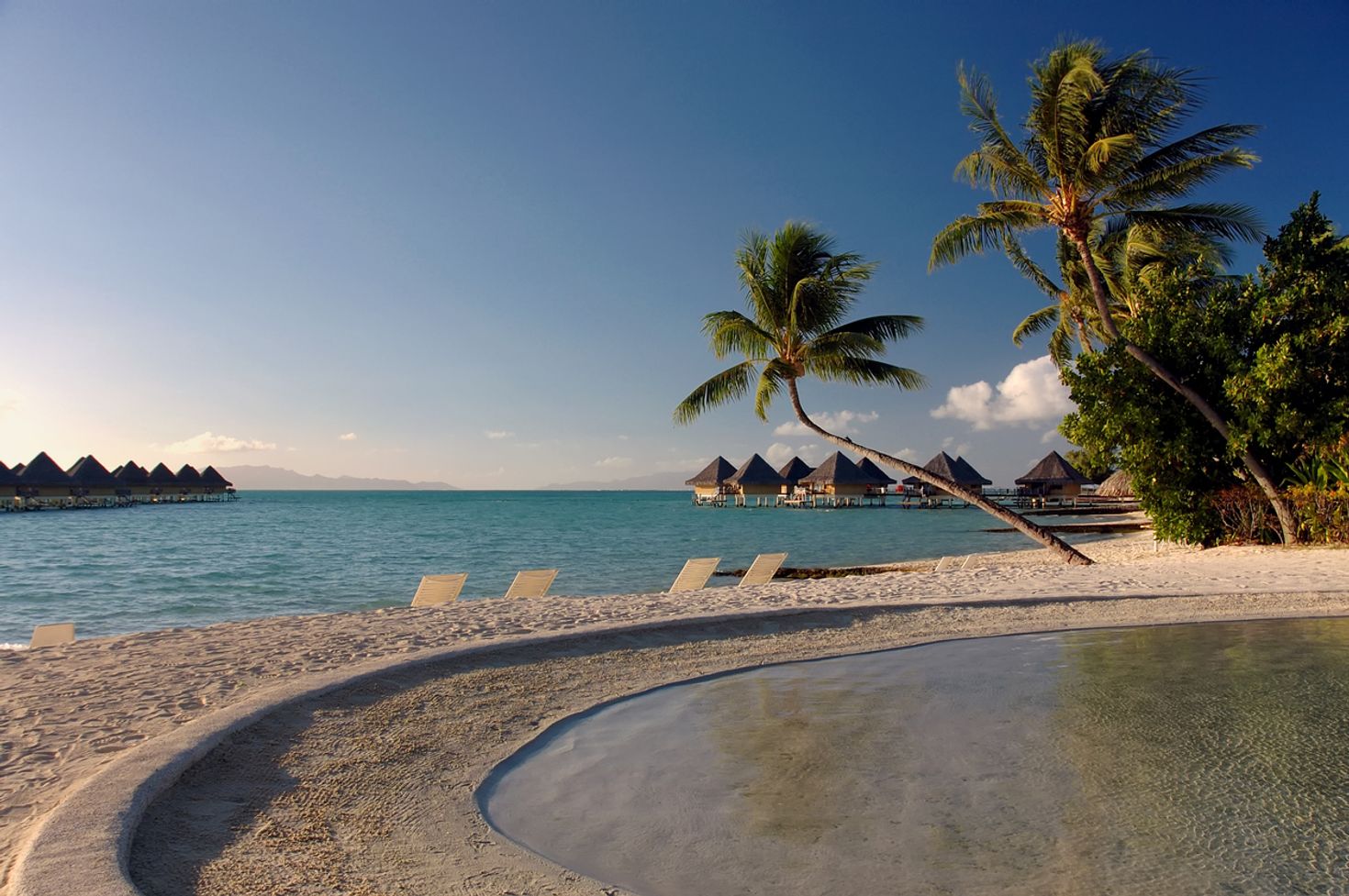 Sunbeds and beach houses overlooking the ocean in Bora Bora. 