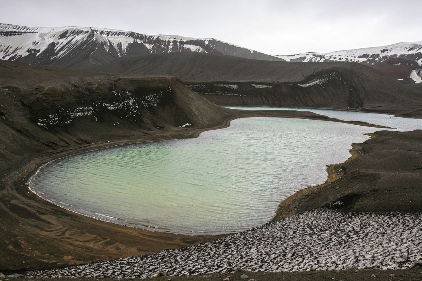 The Deception Island in Antartica with snow-capped mountains in the distance.