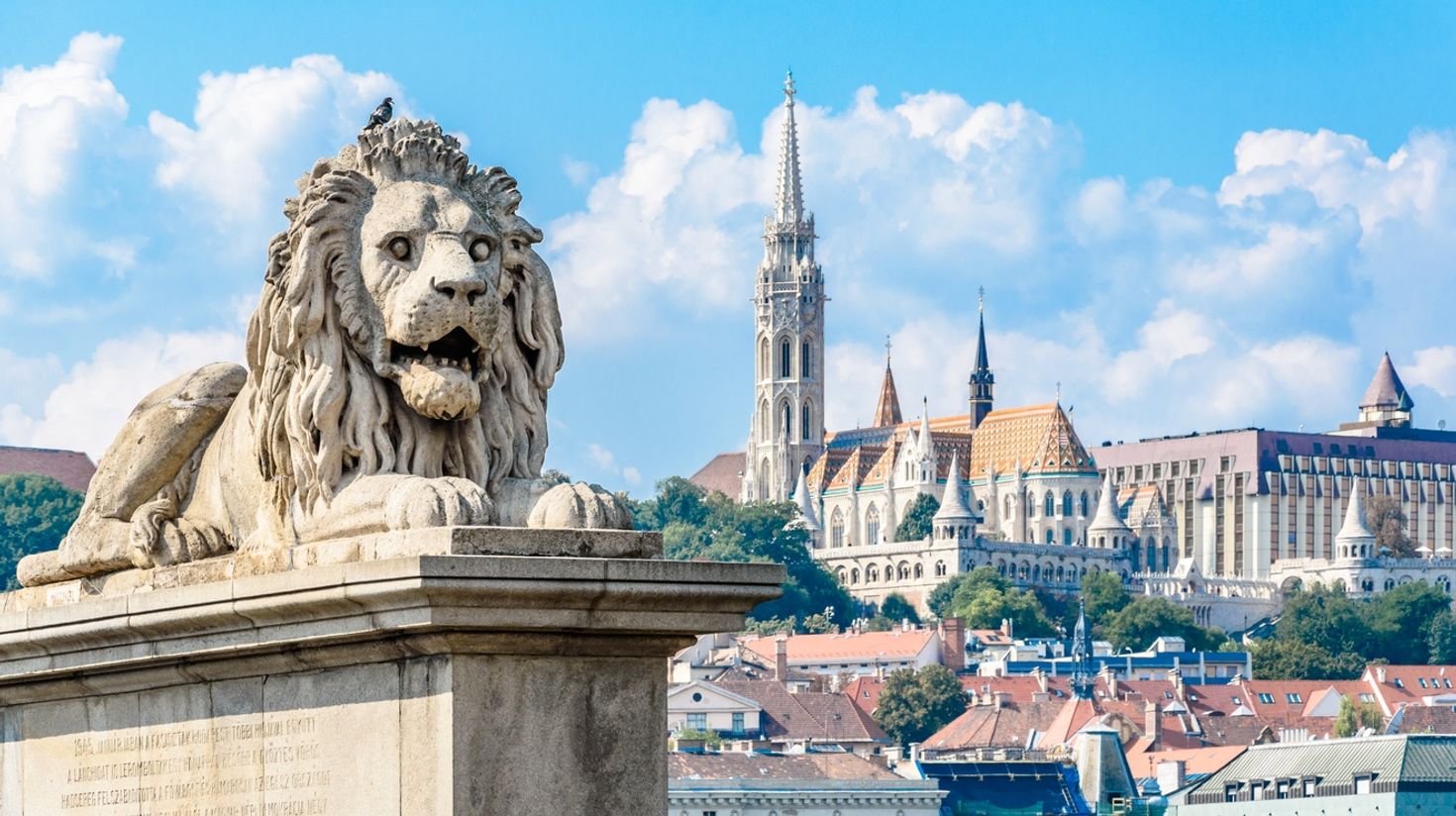 The famous lion statue with a landscape of Budapest in the background in Hungary.