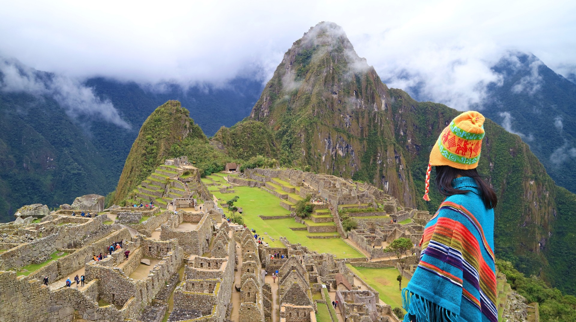 Woman in Poncho and Andean Hat at the ancient Inca Citadel of Machu Picchu, one of the best places to visit in October.
