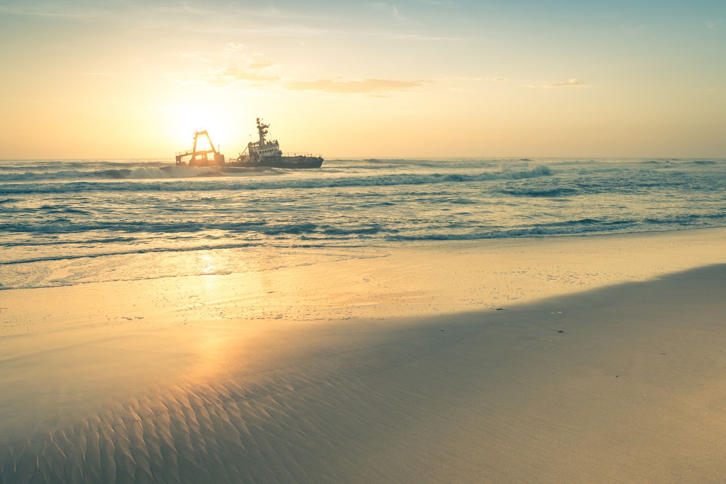 A sunset view with the silhouette of a boat in the sea at Skeleton Coast. 