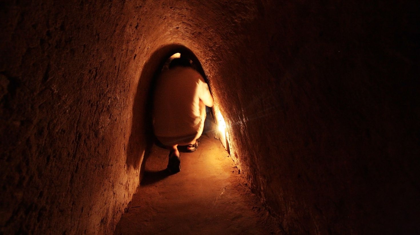A man crawling through Cu Chi Tunnels, a unique thing to do in Vietnam.