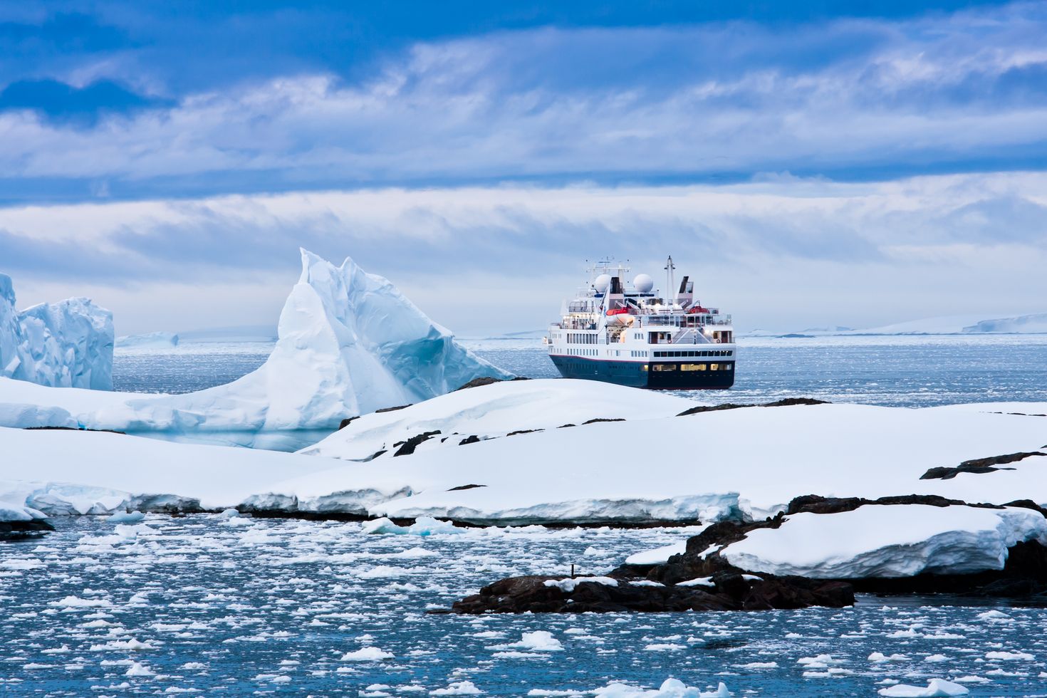 A cruise ship passing by icebergs in Antarctica. 
