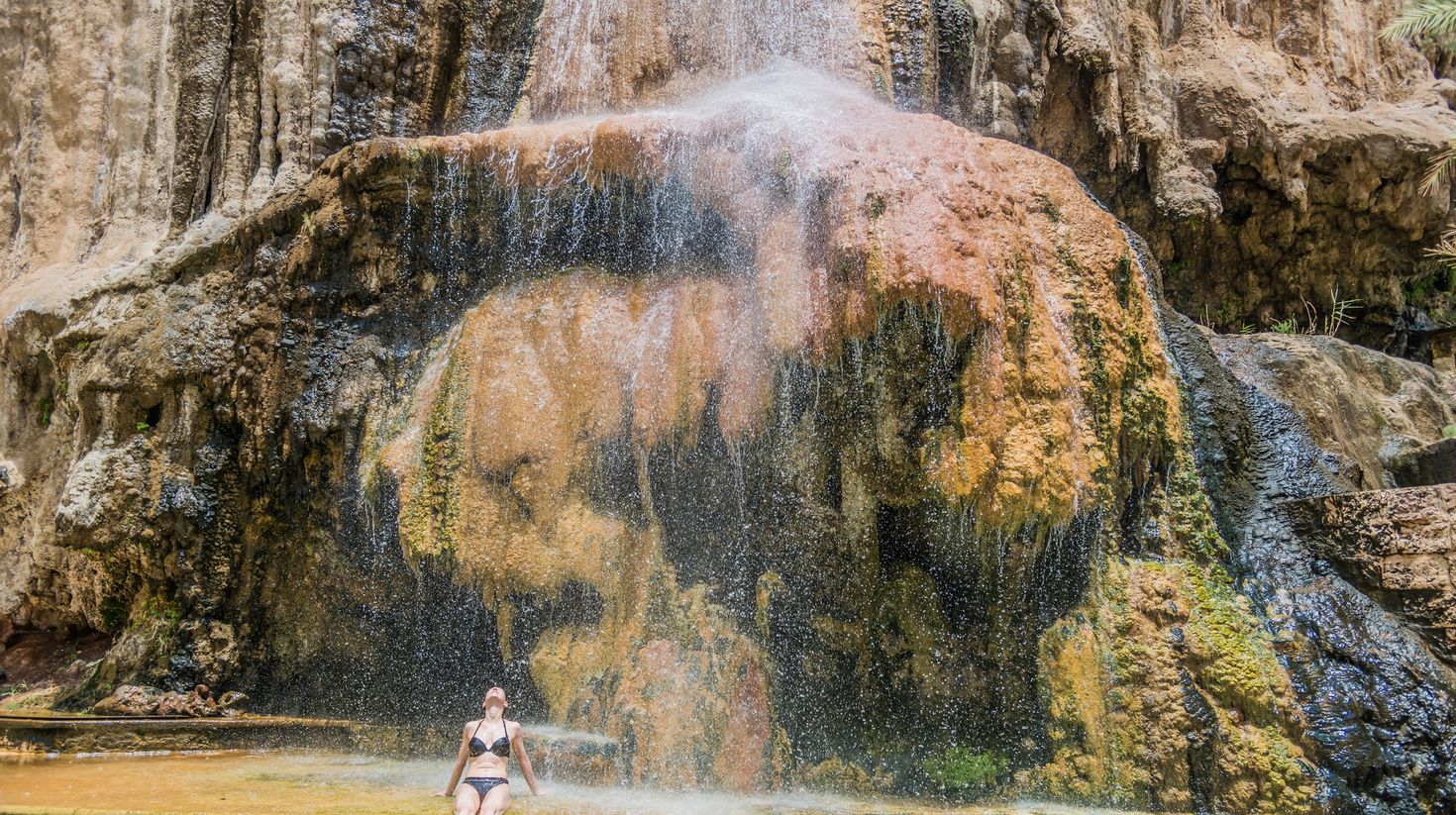 A woman soaking in Jordan's Ma'in Hot Springs Waterfall during winter.