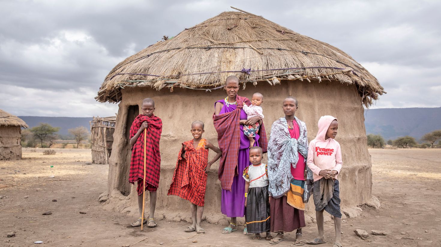Maasai women and a baby outside a village hut.