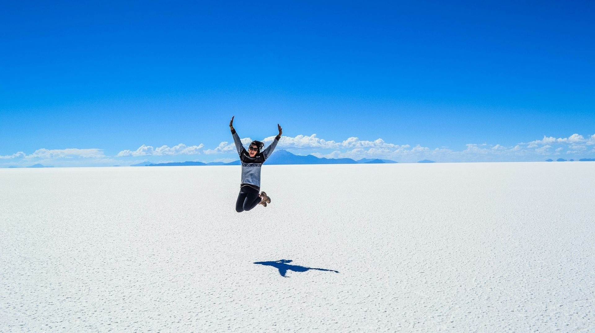 Girl jumping in air on the Uyuni salt flats in Bolivia during a week's stay