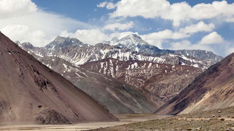 Snow-capped peaks that run down into rugged cliffs form the dramatic backdrop of Cajon del Maipo.