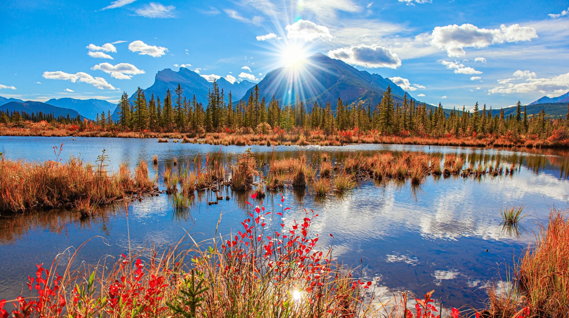 Autumn foliage with Rocky Mountain in the background and the Lake Vermilion reflecting the clouds in Canada in October.