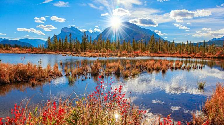 Autumn foliage with Rocky Mountain in the background and the Lake Vermilion reflecting the clouds in Canada in October.