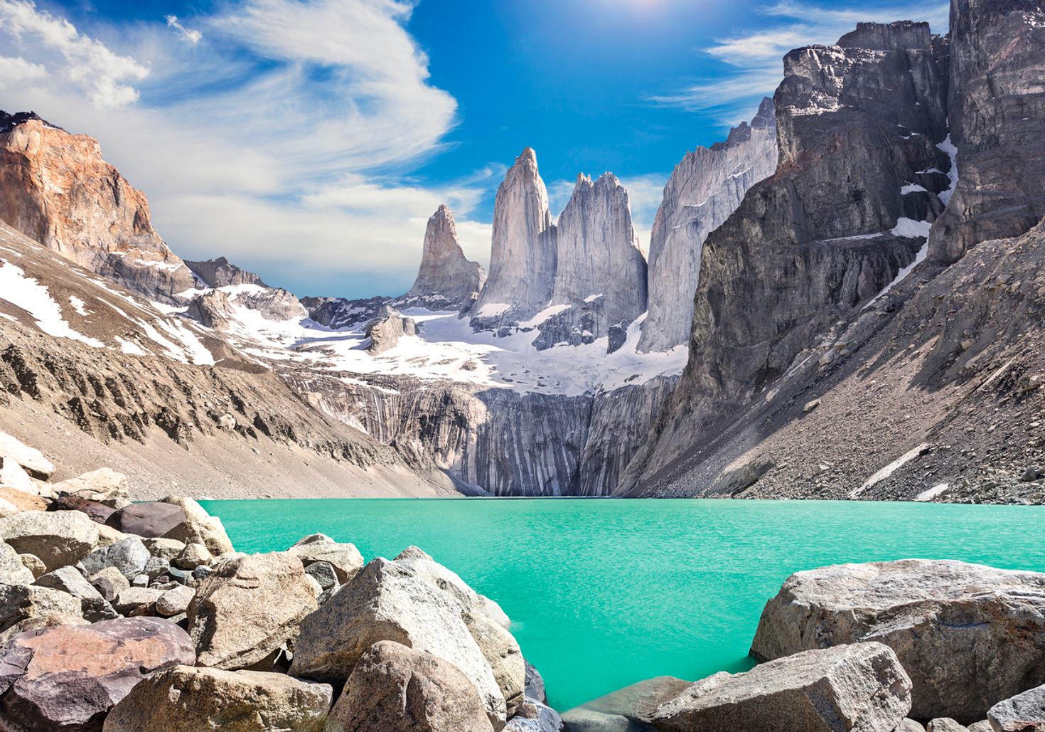 Three towering rock formations against the backdrop of turquoise blue lake at Torres del Paine National Park.