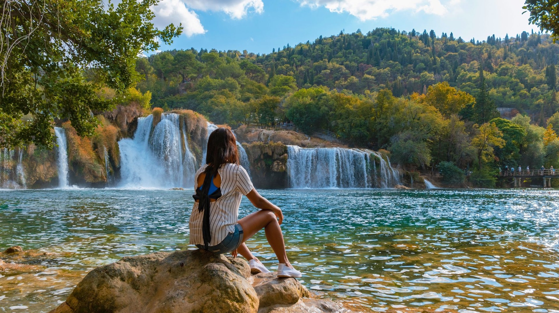 A woman tourist admiring the beauty of waterfall in Krka National Park on her 4 days in Croatia.