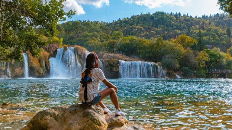 A woman tourist admiring the beauty of waterfall in Krka National Park on her 4 days in Croatia.
