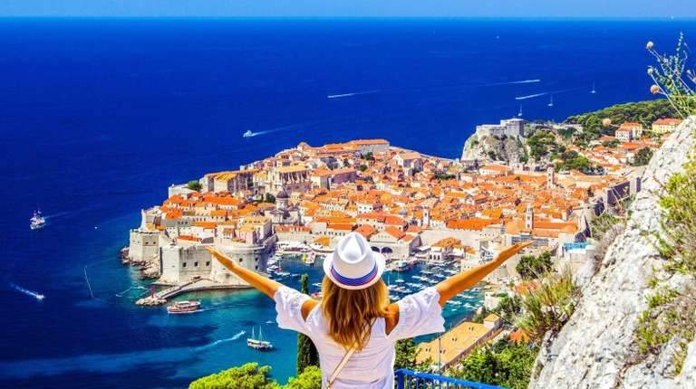 A happy girl with raised arms admiring the beauty of Dubrovnik during her 5 days in Croatia trip.