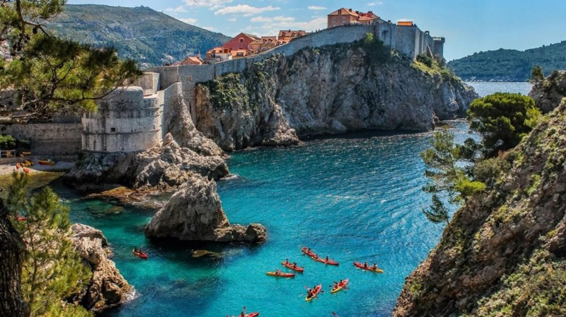Paddle through crystal-clear waters and soak up the stunning coastline while enjoying kayaking adventures in Croatia in June. People kayaking on a clear day in Dubrovnik in Croatia in June.
