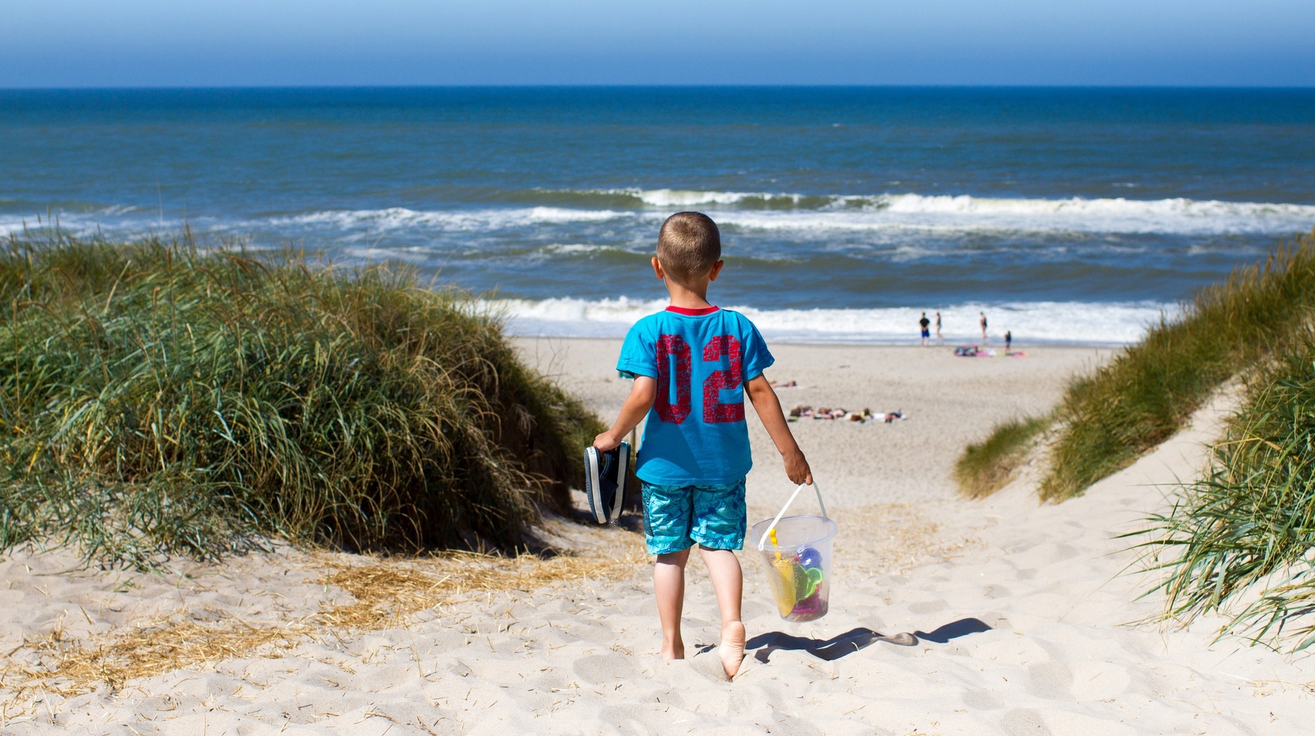 Visit Denmark in August to relax by the beautiful Danish coast. A boy headed to the beach on his trip to Denmark in August.