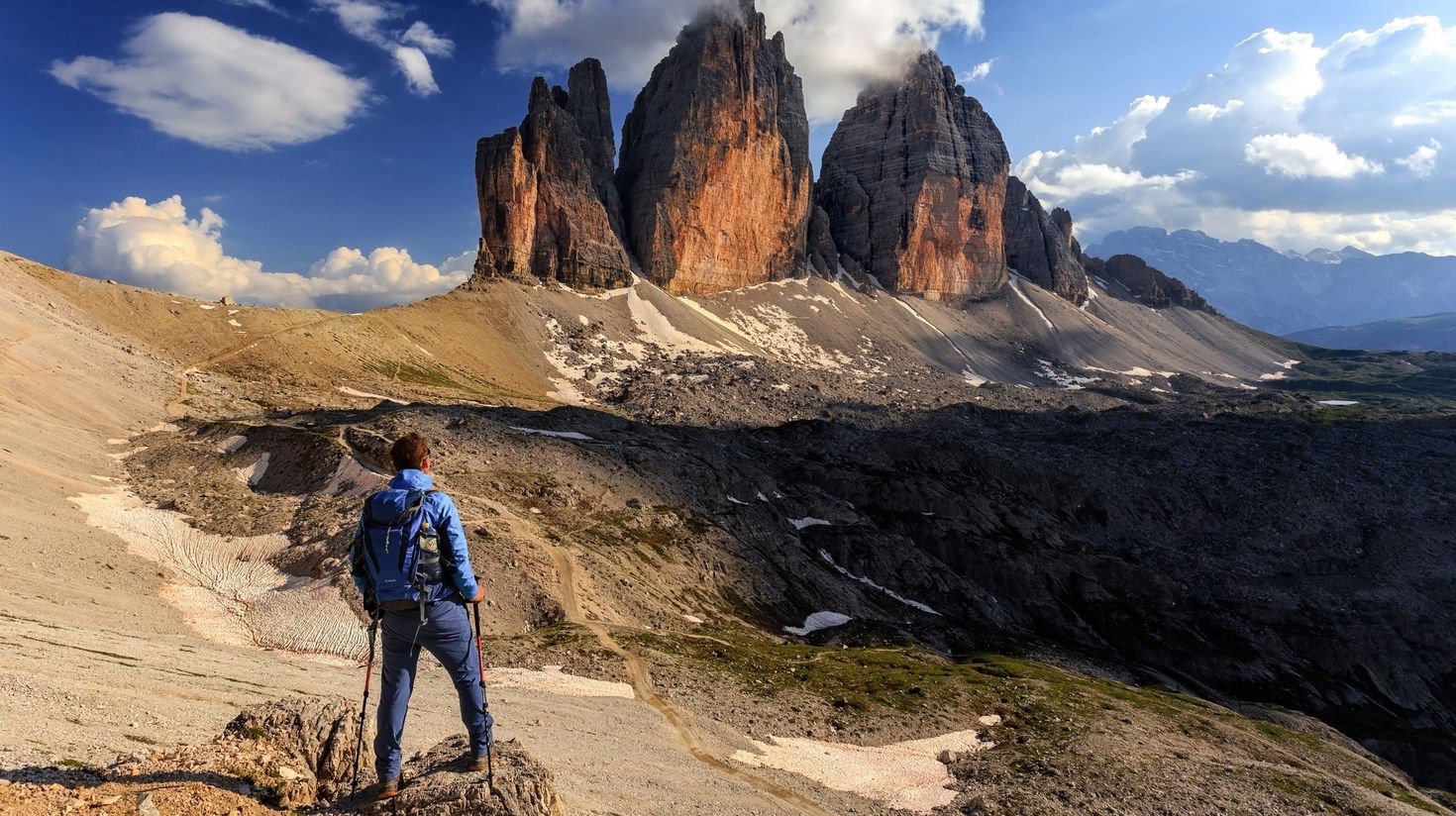 A man hiking in the Dolomites admires the view in Tre Cime di Lavaredo in Italy. 