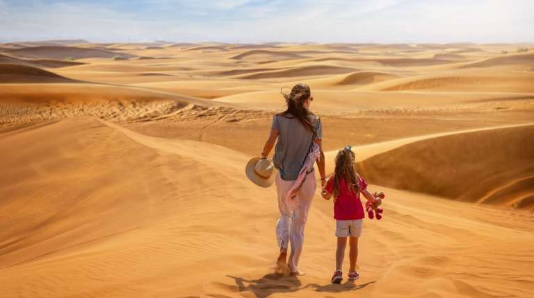A mother and daughter in the sand dunes when spending a week in Dubai.