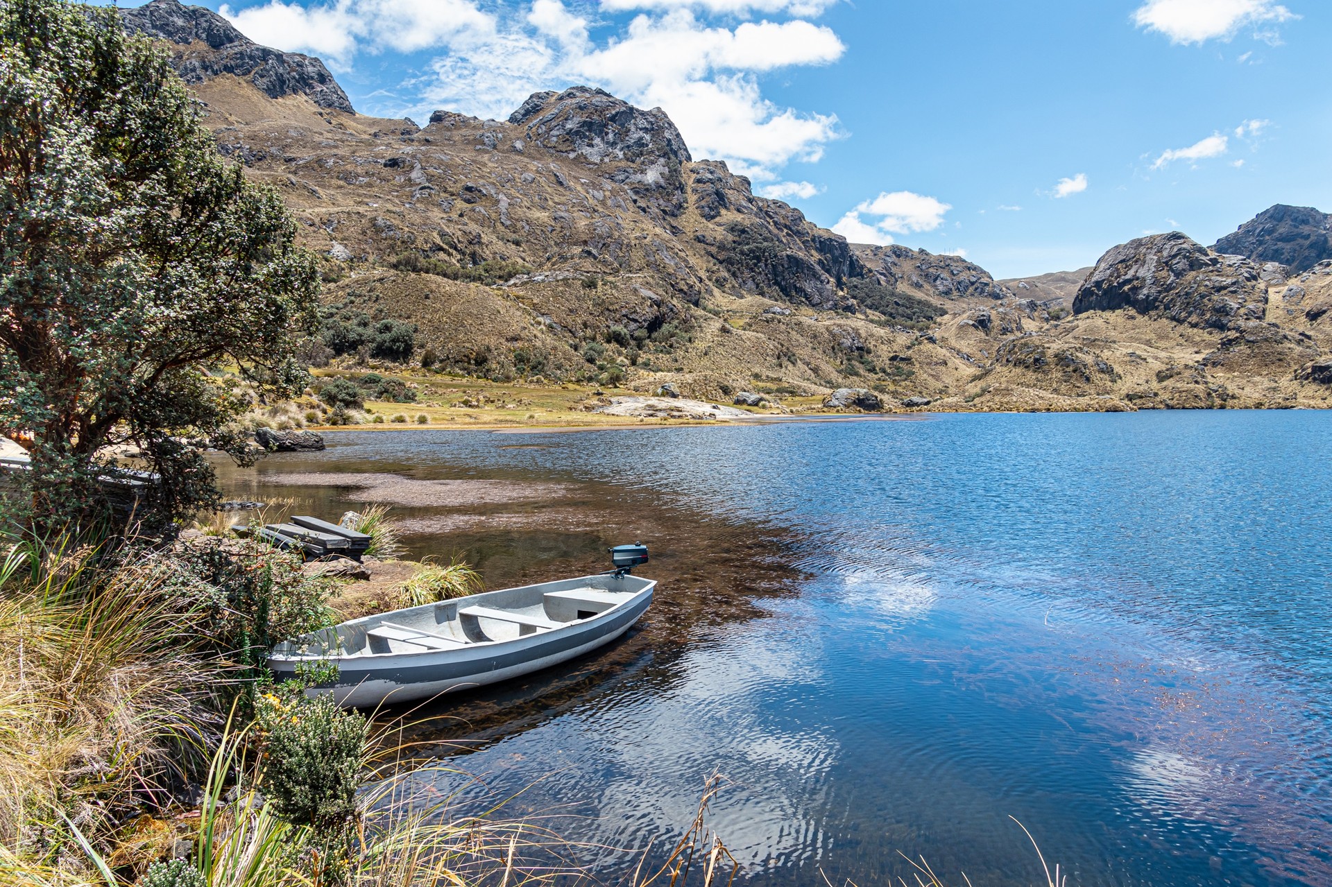 Mountain lake Toreadora with a boat in Cajas National Park on a clear day during your 6 days in Ecuador.